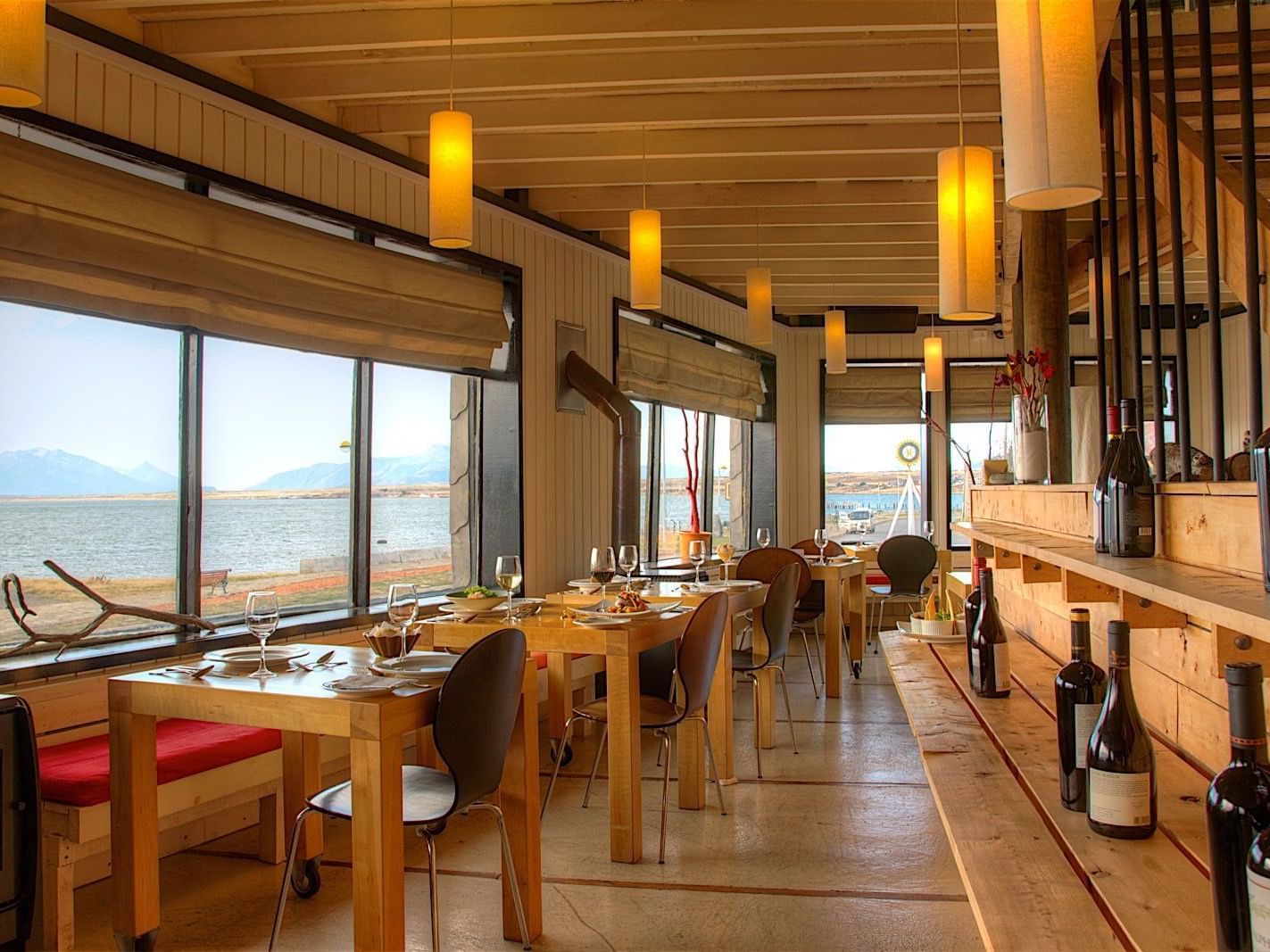 Elegant Kosten Restaurant with set tables and large windows overlooking the water at NOI Indigo Patagonia