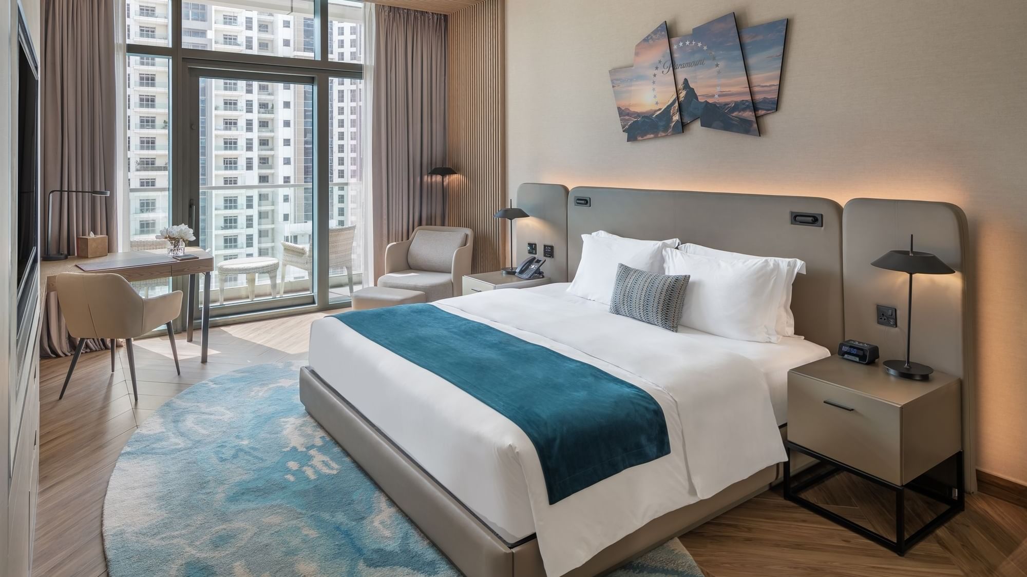 Comfy bed and work desk by the large window in Scene Room City View at Paramount Hotel Midtown