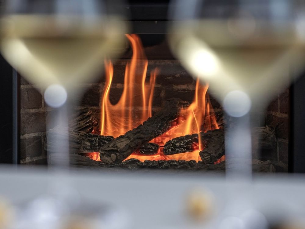 Close-up of two wine glasses in front of a fireplace at Warwick Le Crystal Montreal