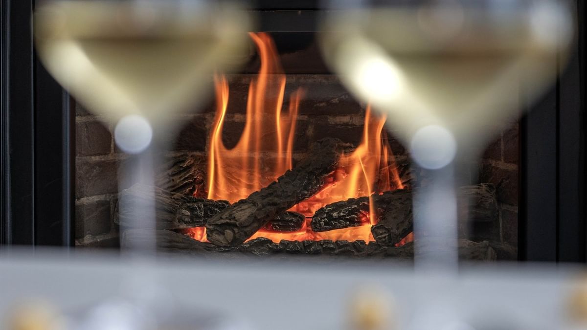 Glasses of wine in front of a fireplace in the Penthouse Sainte-Catherine at Warwick Le Crystal Montreal.