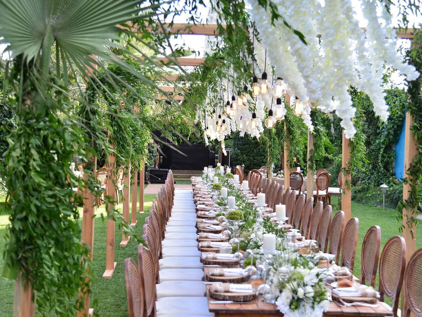  Titanic Business Kartal’da açık alanda, düğün için çiçeklerle süslenmiş uzun yemek masası ve sandalyelerle şık bir düzenleme.