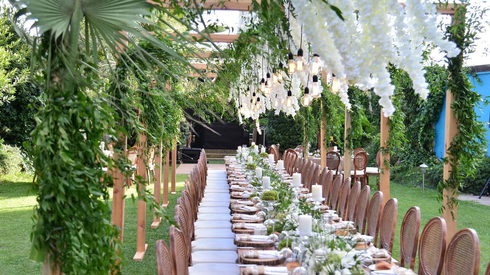 Long dining table arranged with chairs and decorated with flowers for a wedding event outdoors at Titanic Business Kartal