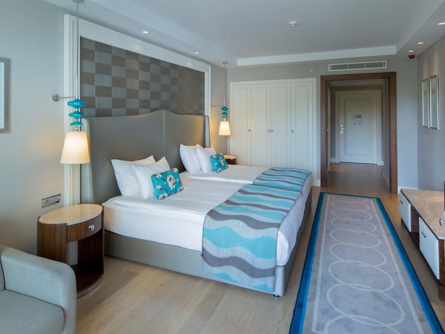Lounger & nightstand by the bed in Handicap Room with wooden floors at Titanic Deluxe Golf Belek