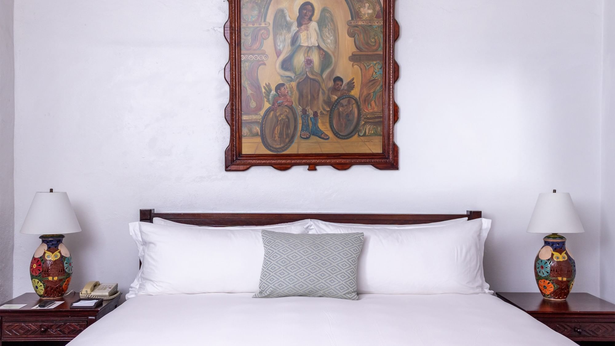 Cama king con almohadas y arte colonial en la habitación Superior King de Quinta Real Oaxaca en Oaxaca de Juárez