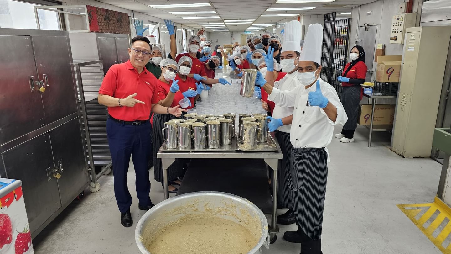 Kitchen with workers in uniforms and protective gloves preparing food at Sunway Putra Hotel