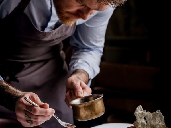 Chef plating a dish with precision at The Capital Hotel, Apartments & Townhouse - London.