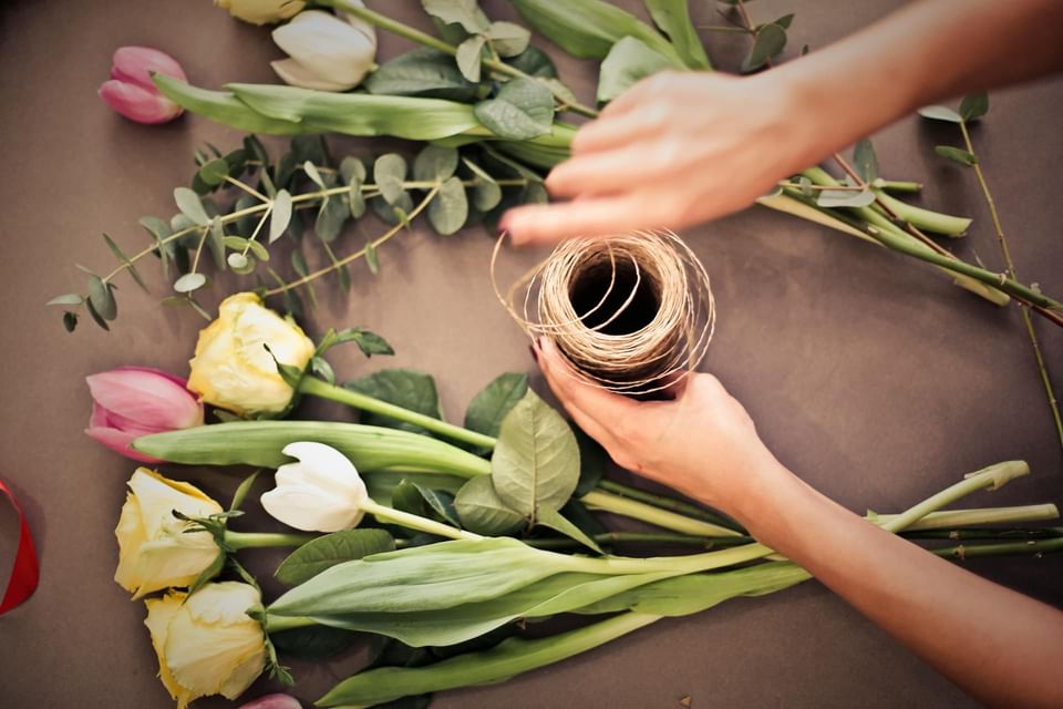 Hands arranging flowers with twine on a table at Ananea Madivaru Maldives