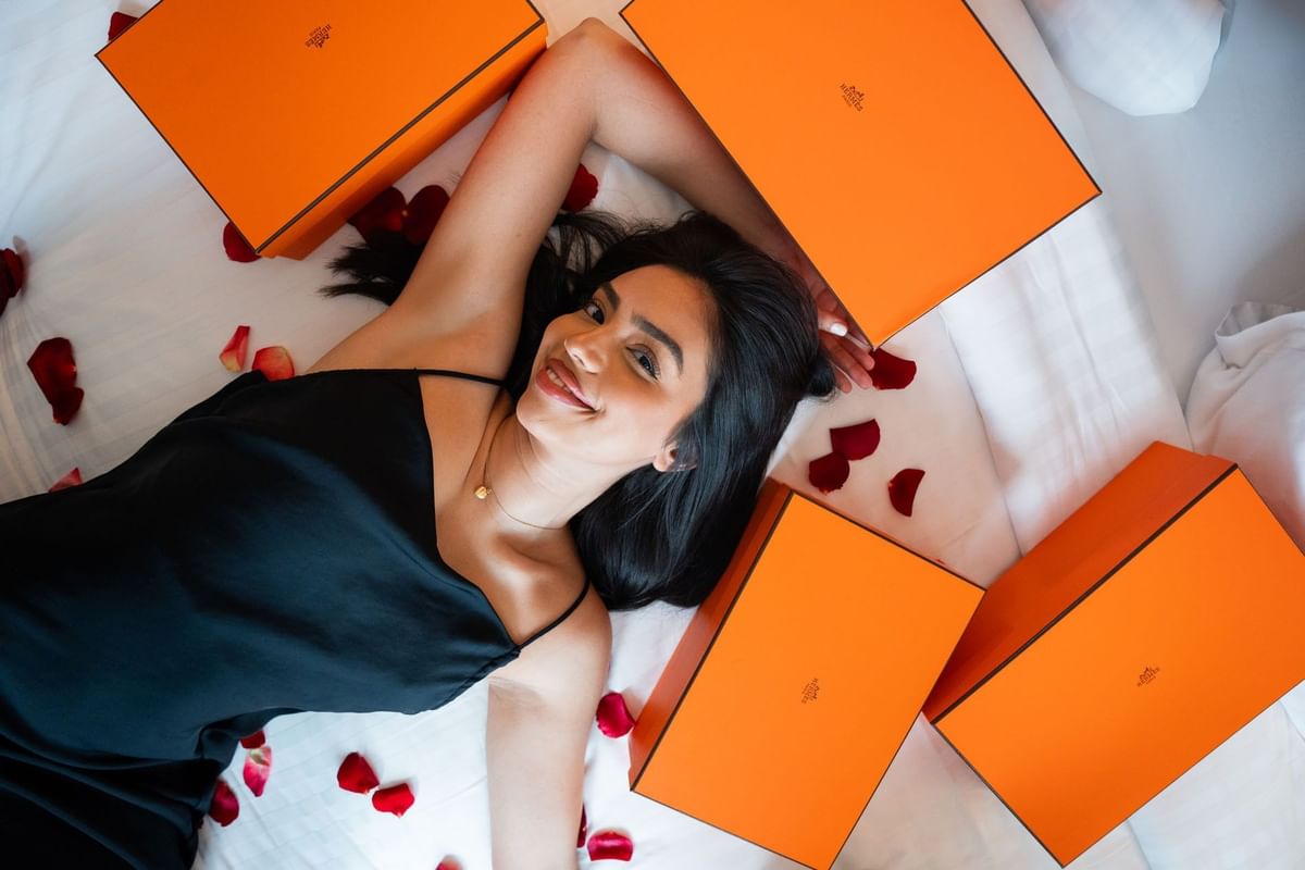 Guest by orange gift boxes under rose petals, surrounding white linens at Saja by Warwick Paris Champs Elysées