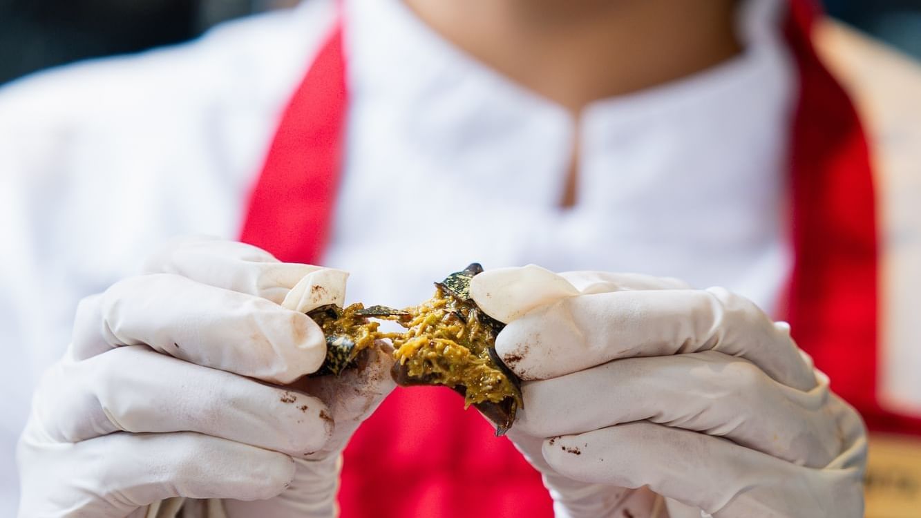 Chef with white gloves at Paramount Hotel Dubai breaking open a rich chocolate with a green filling