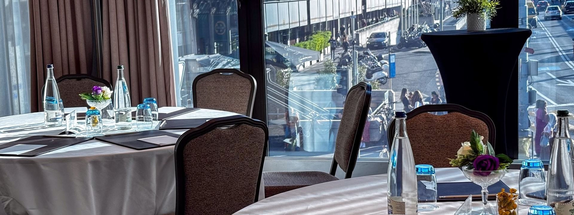 Tan chairs surrounding a U-shaped wooden table under a large screen in Rigi + Cervin at Warwick Geneva