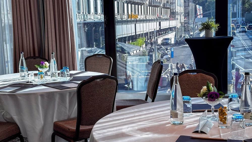 Tan chairs surrounding a U-shaped wooden table under a large screen in Rigi + Cervin at Warwick Geneva