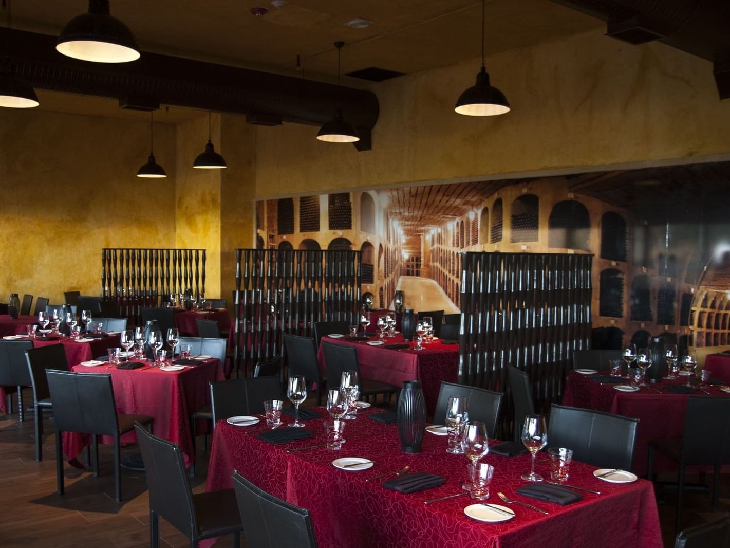 Restaurant dining tables with red table linen and black chairs in La bodega at Grand Fiesta Americana Los Cabos All Inclusive Golf and Spa
