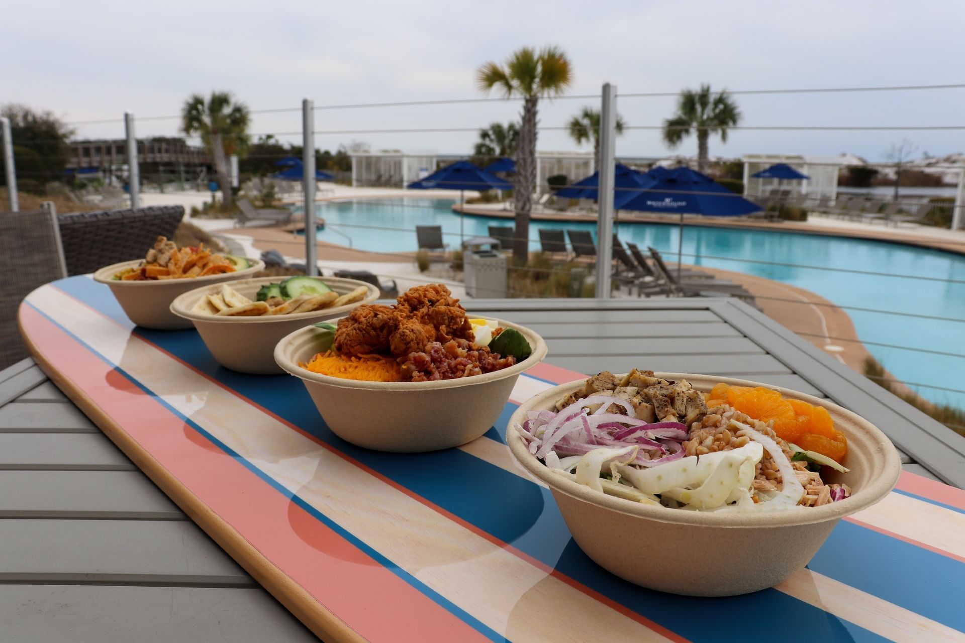 Variety of dishes served on the balcony with a pool view at Watersound Inn