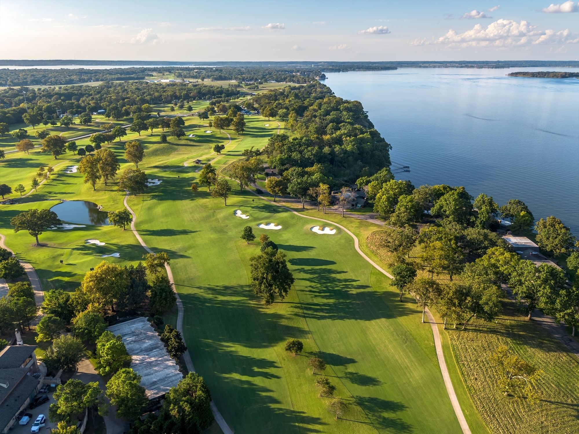 Aerial perspective of a lush green golf course running alongside a large blue lake at Shangri-La Resort and Golf Club