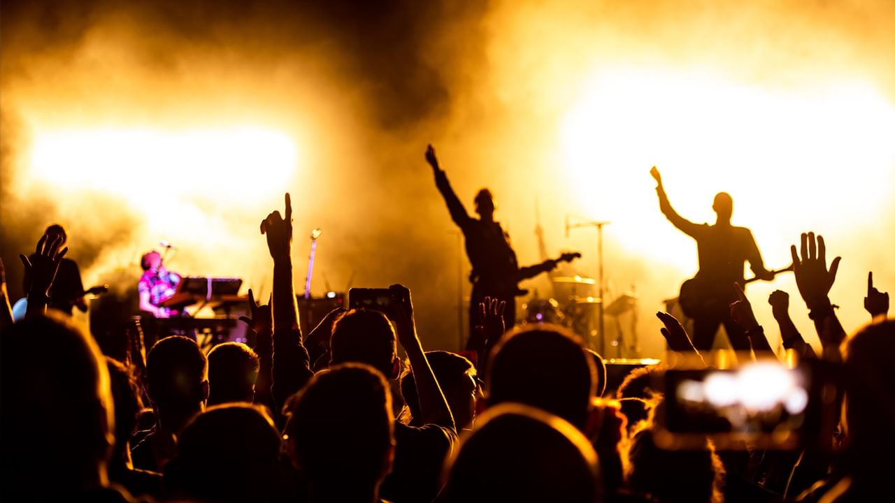 A lively crowd at a concert with hands raised, spotlights, and performers on stage for Country Hearts: Valentine’s Day at the Lyric.