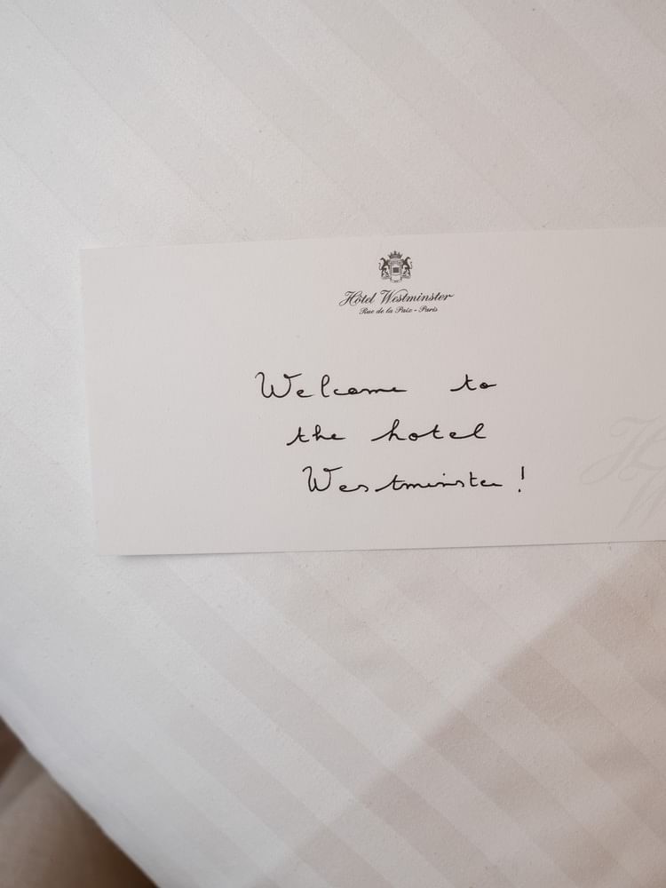 Handwritten welcome card on white linens reading Welcome to the hotel Westminster with hotel logo at top.
