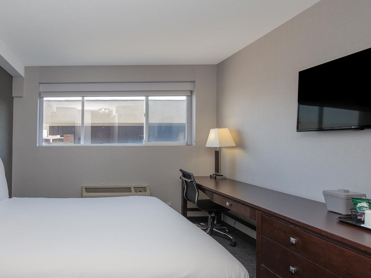 Bed in a room with window and desk.