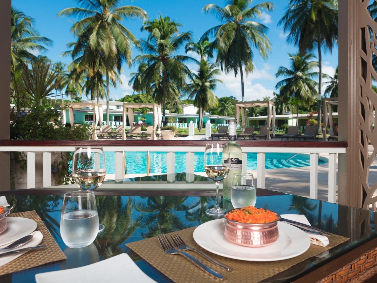 Dining area with dishes served on a table by swimming pool and lawn area at All Seasons Resort Europa