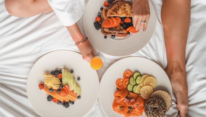 Vue du dessus d'une femme prenant son petit-déjeuner sur le lit de l'hôtel X Toronto