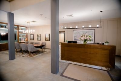 Wooden reception desk beside a spacious conference table area with stylish chairs at La Tourelle Hotel and Spa