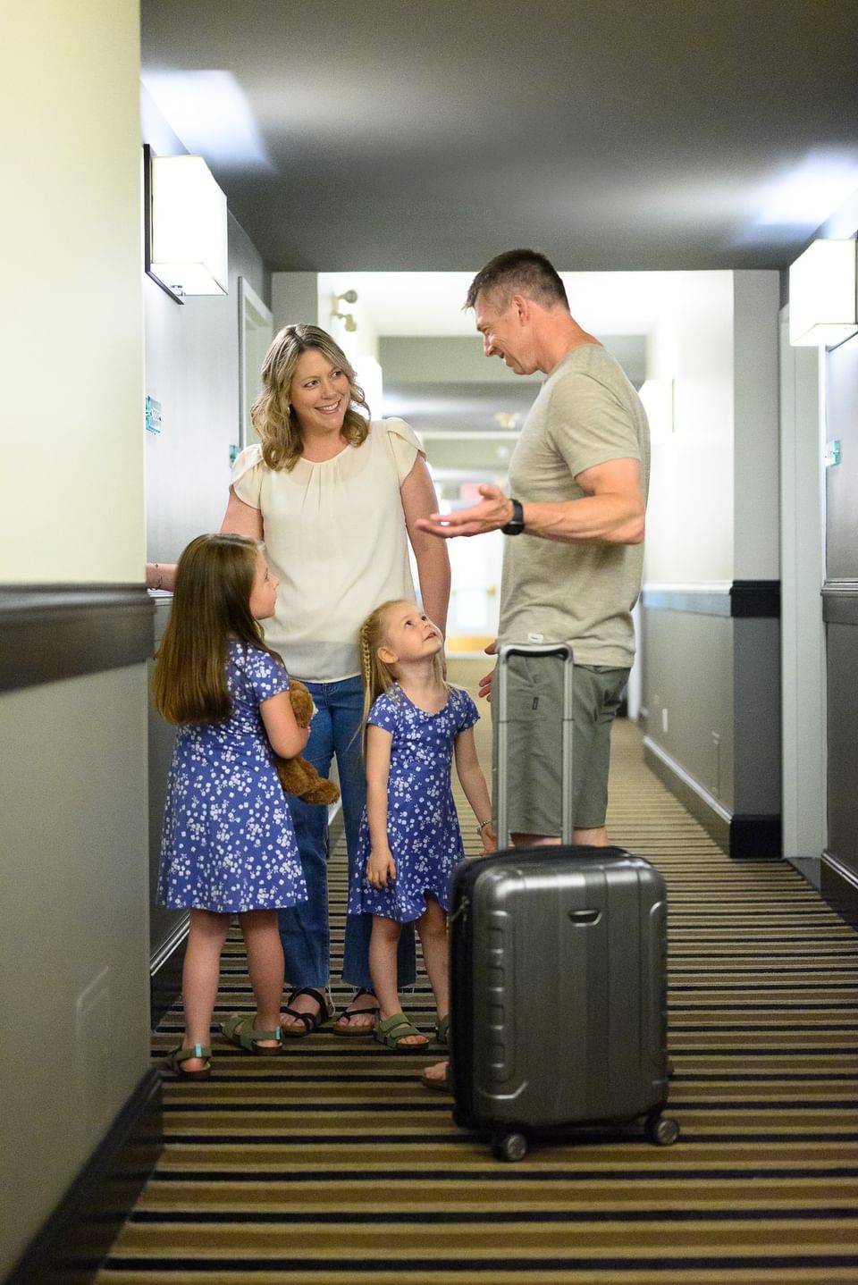 Family with a rolling suitcase standing in a hallway at Rodd Miramichi River, an apartment hotel in Miramichi, NB 