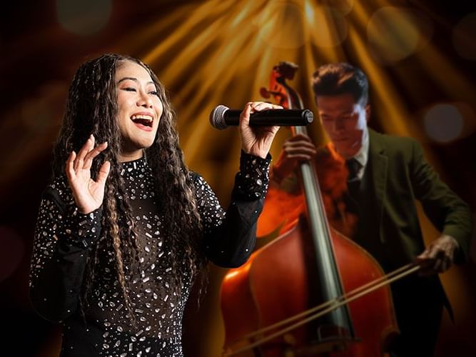 A woman sings passionately while a man plays the double bass, creating a harmonious musical atmosphere.