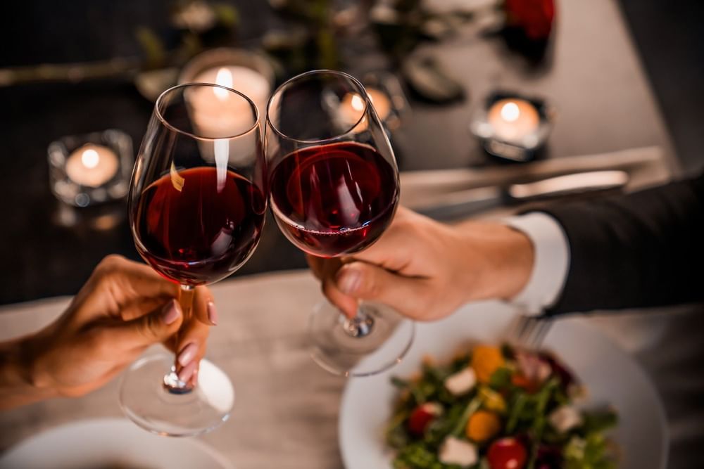 Primer plano de una pareja brindando con copas de vino en Live Aqua Resorts