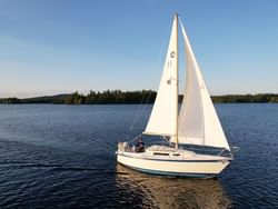 A sailboat glides across the Sail Adirondacks LLC near High Peaks Resort