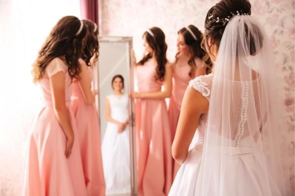 Bride looking into the mirror surrounded by her bridesmaids