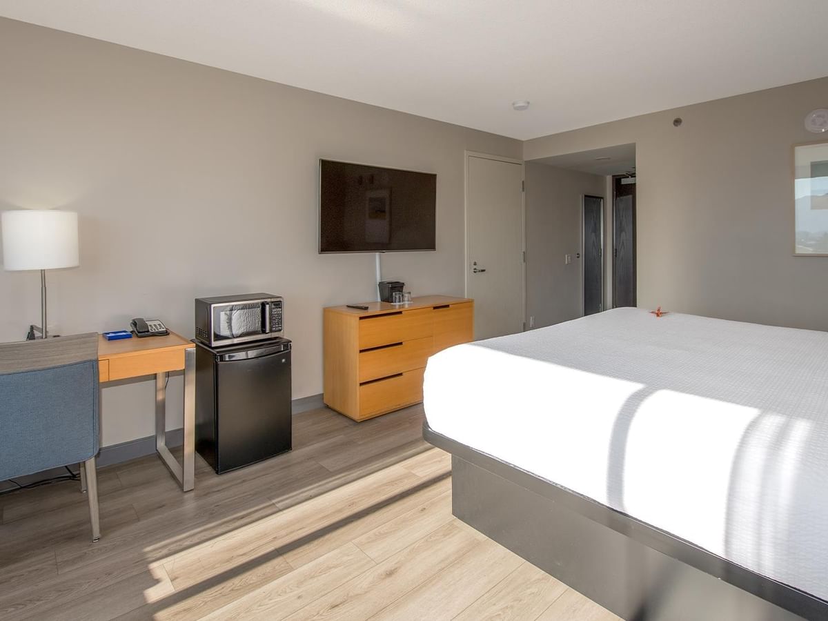 Hotel room with king bed, mini fridge, microwave, TV, and work desk.