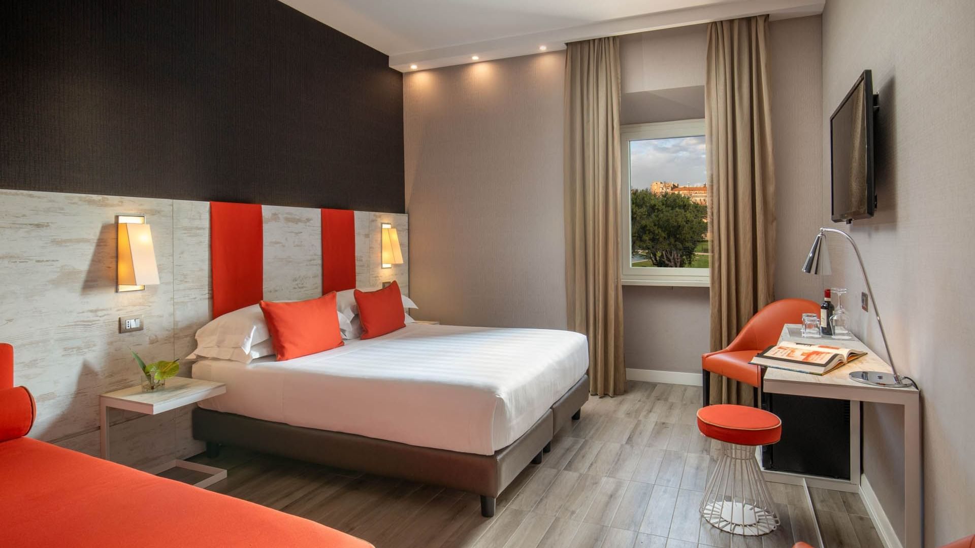 Bright Deluxe Room at The Guardian Hotel with a comfy bed, work area, and a view of greenery outside