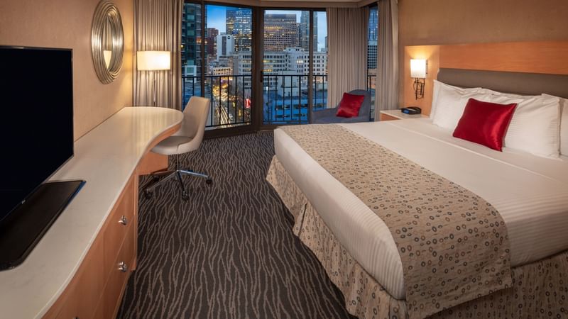 Bed with workspace and city view in Premier King Room at Warwick Hotels & Resorts