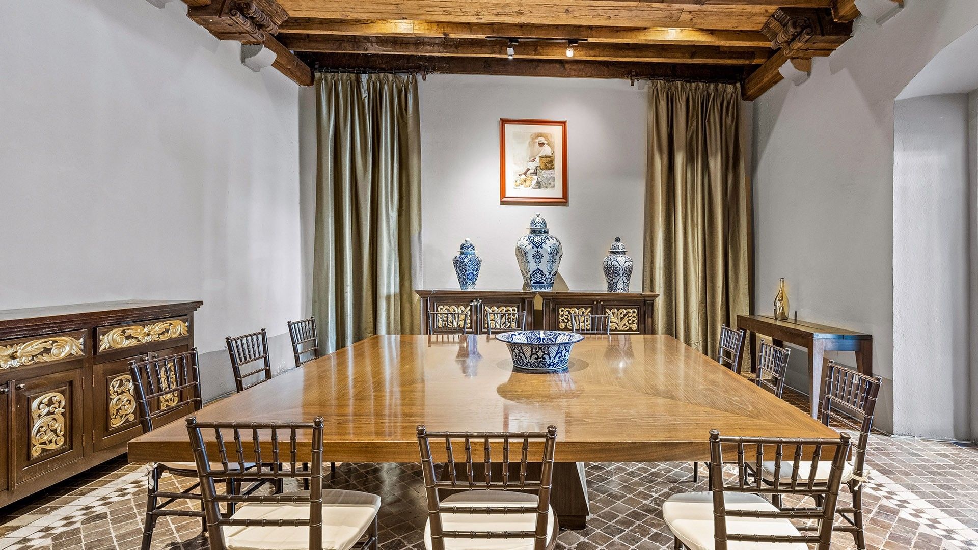 Large square wooden dining table with blue and white pottery and patterned floors at Quinta Real Puebla