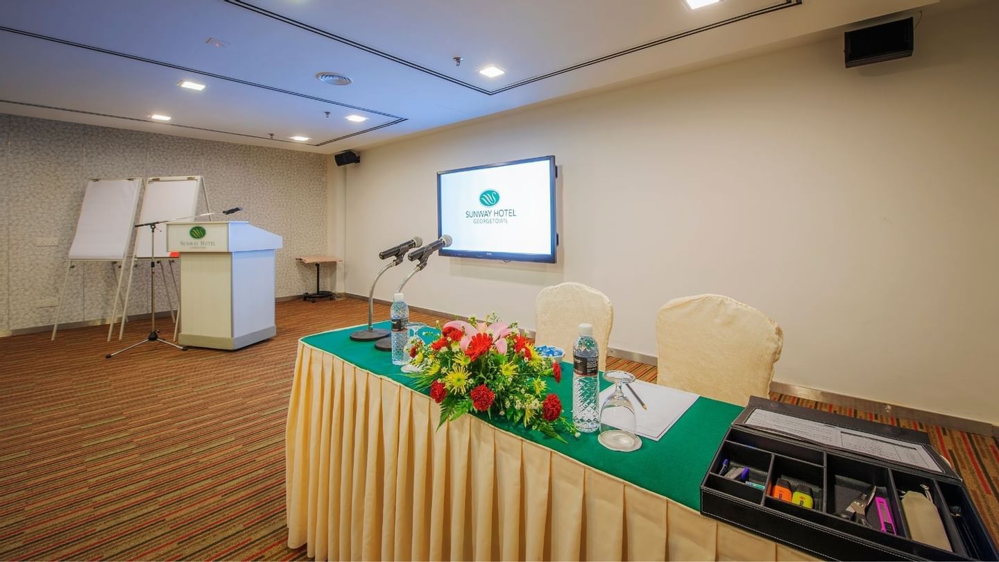 Conference room setup with microphones on a table with flowers at Sunway Hotel Georgetown