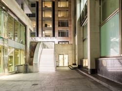 A modern, illuminated staircase leads up to an entrance, surrounded by sleek glass buildings near ReStays Ottawa