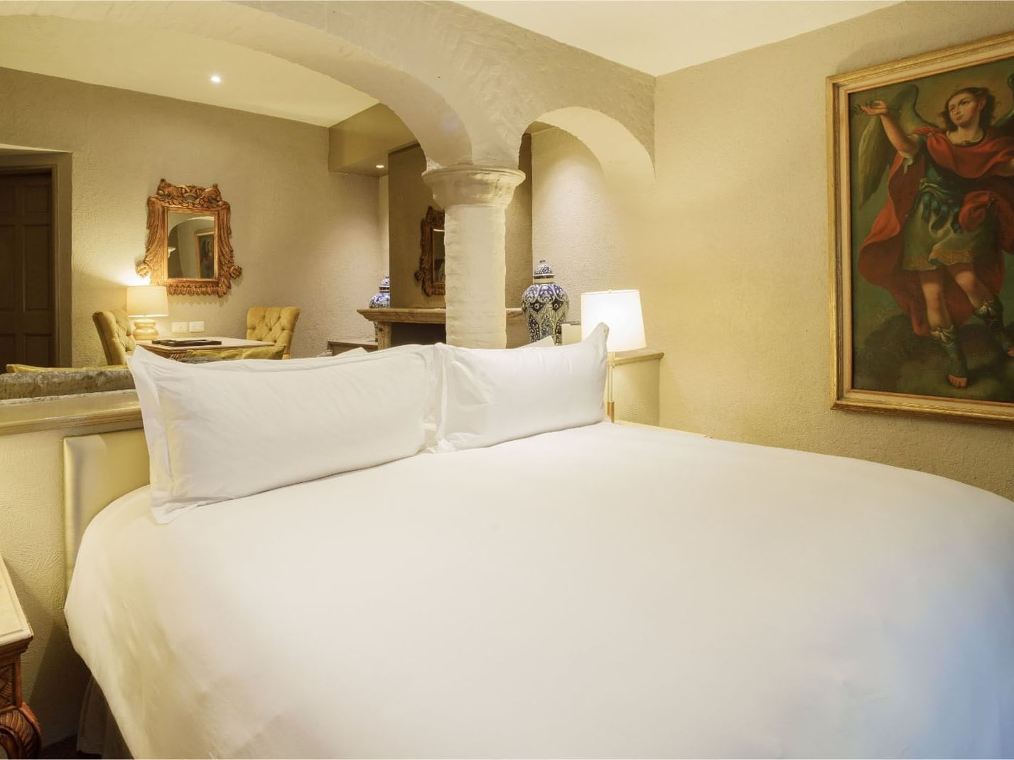King Master Suite with white linens, stone arches, and a classical angel painting at Quinta Real Guadalajara