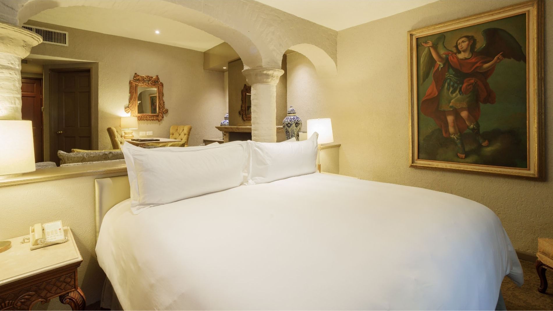 King Master Suite with white linens, stone arches, and a classical angel painting at Quinta Real Guadalajara