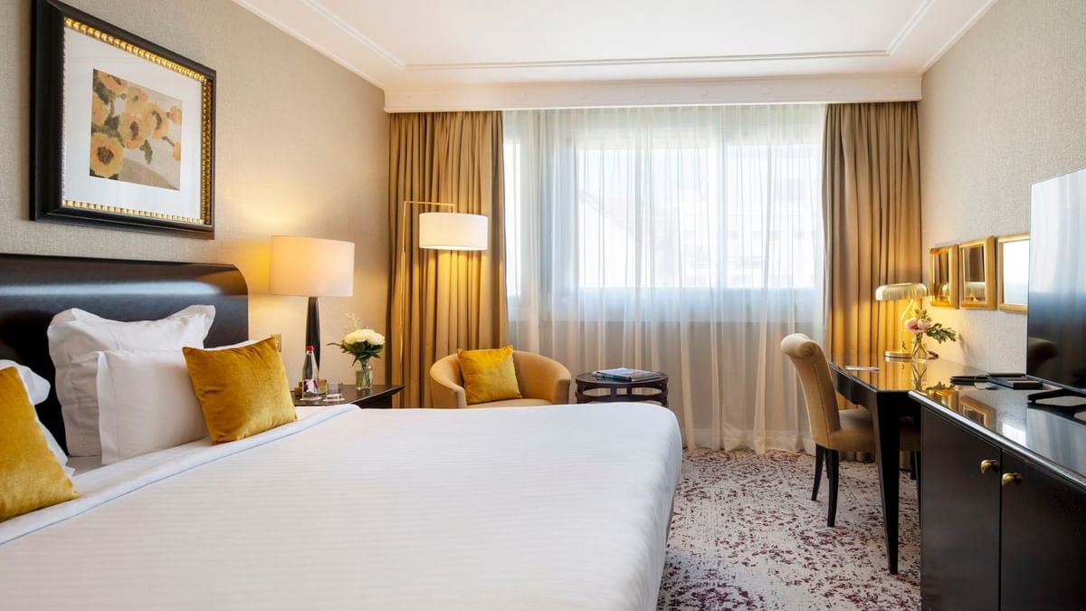 The Montaigne Suite features Desk with a gold lamp by a cozy armchair at Warwick Paris Champs Elysées