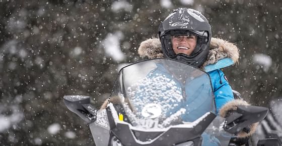 A woman snowmobiling in the snow near Hotel Jackson