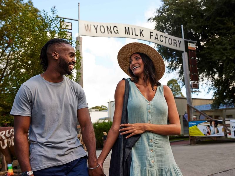 A couple holding hands in front of Wyong Milk Factory near Mercure Kooindah Waters