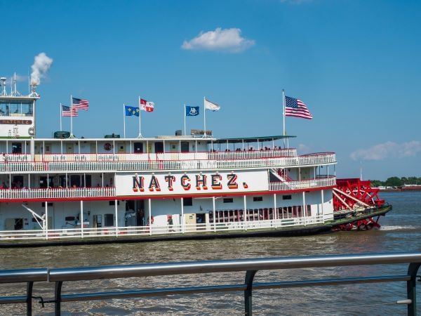 Natchez steamboat gliding gracefully near La Galerie Hotel