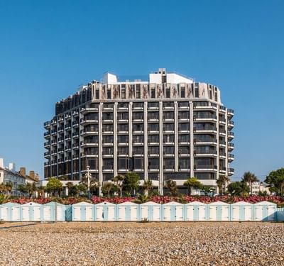 Modern hotel building with balconies and adjacent beach huts on a pebble beach at The View Hotel Eastbourne