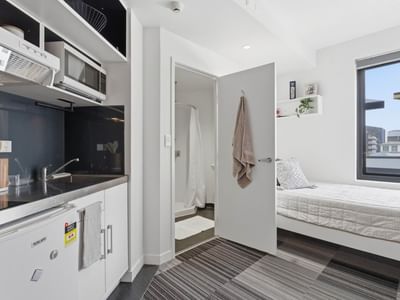 Small room with kitchenette and bed at UniLodge Auckland City.