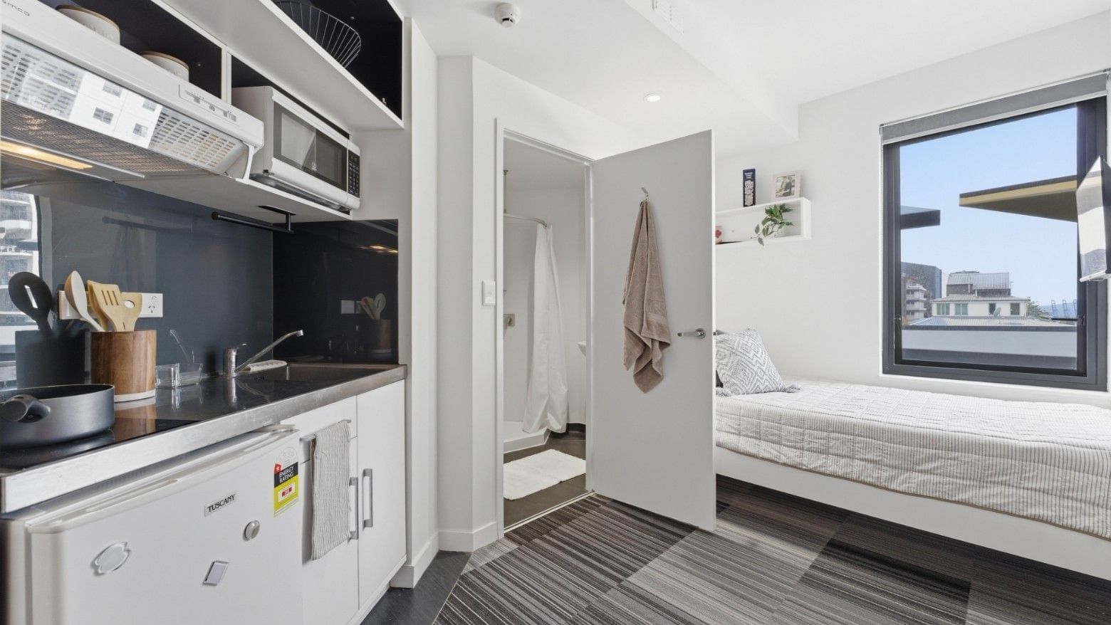 Small room with kitchenette and bed at UniLodge Auckland City.