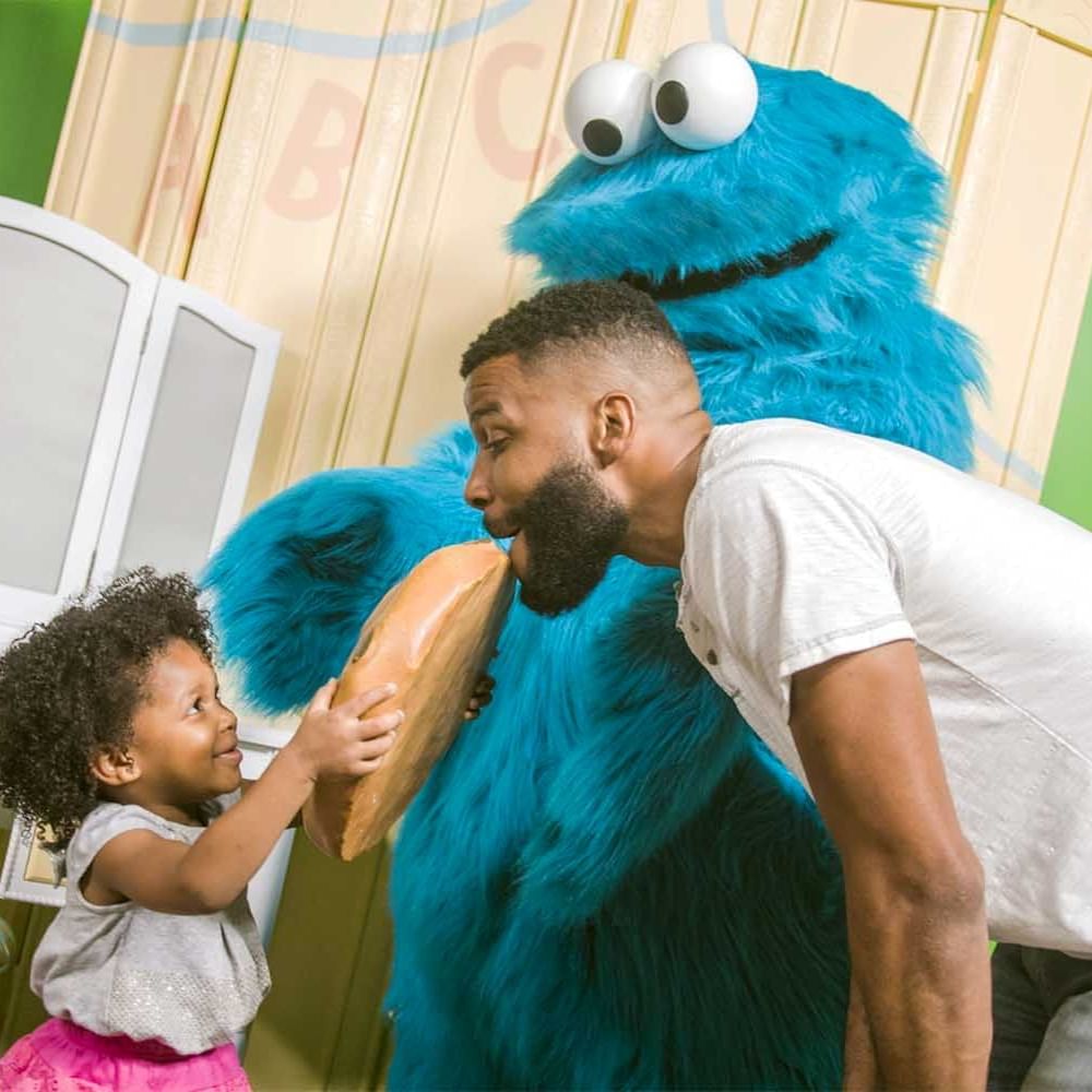 a little girl and her dad with a Sesame Street character
