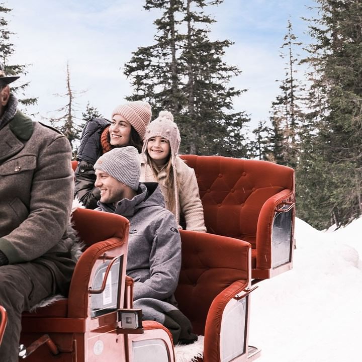 Gruppe von Menschen, die auf einem Pferdeschlitten durch den Schnee fahren.