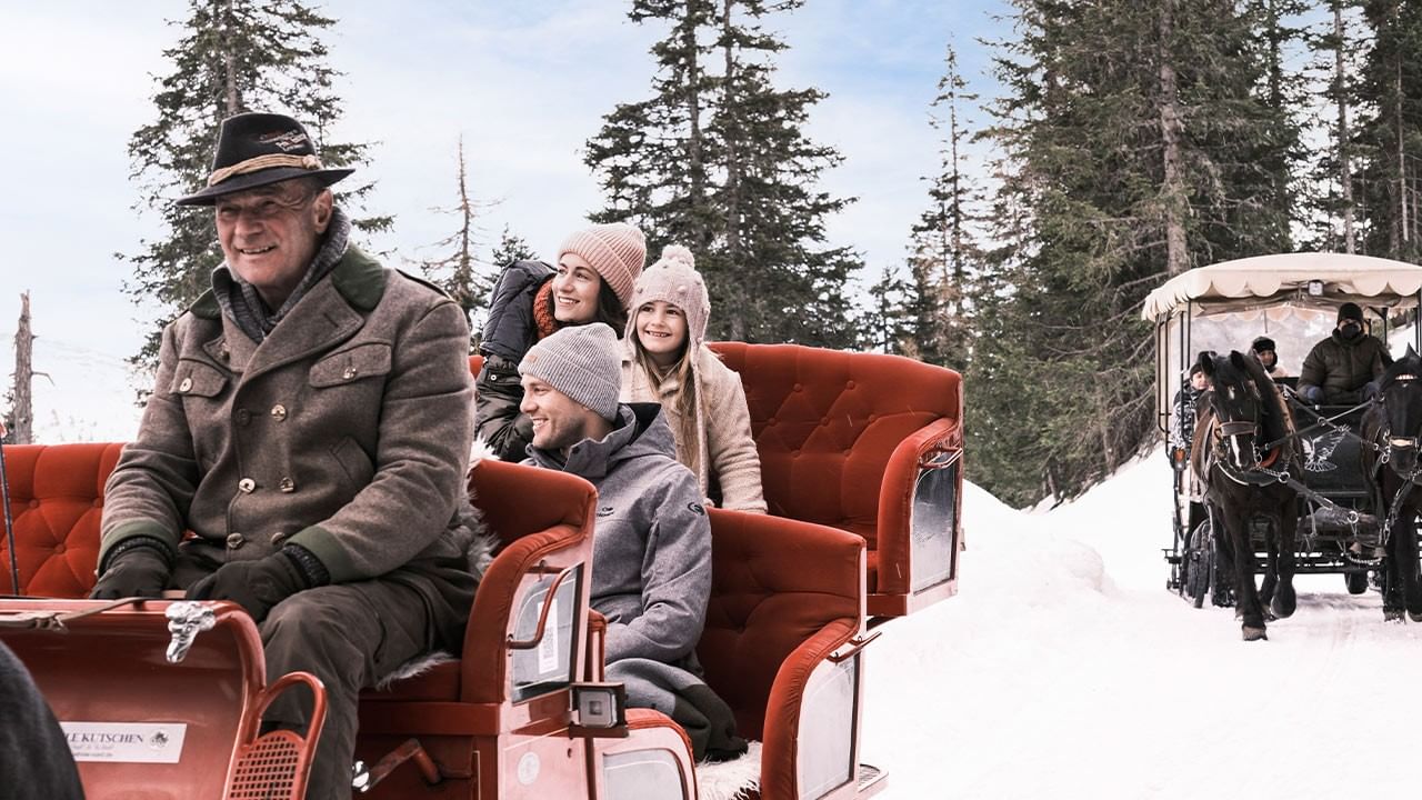 Famiglia felice su una slitta trainata da cavalli in una foresta innevata.
