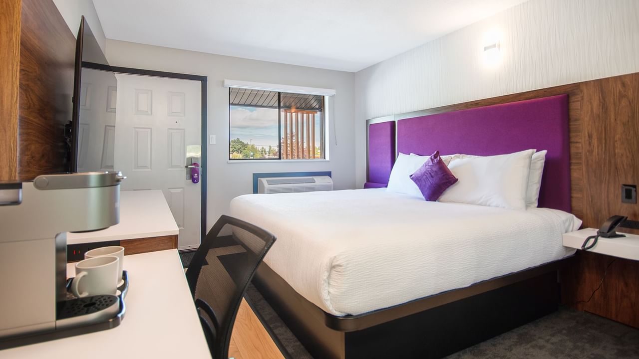 Hotel guest room with a king bed, flat screen TV, and work desk