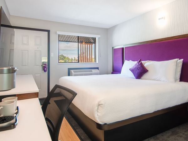 Hotel guestroom with king bed, TV, work desk and coffee maker