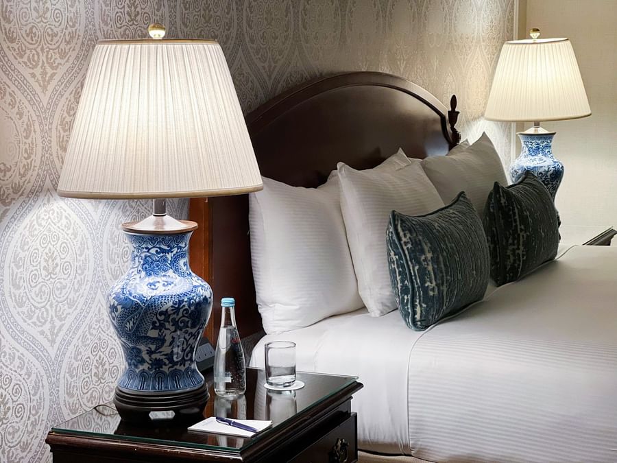 Elegant room with bed, blue and white lamp, and glass table at Warwick New York.
